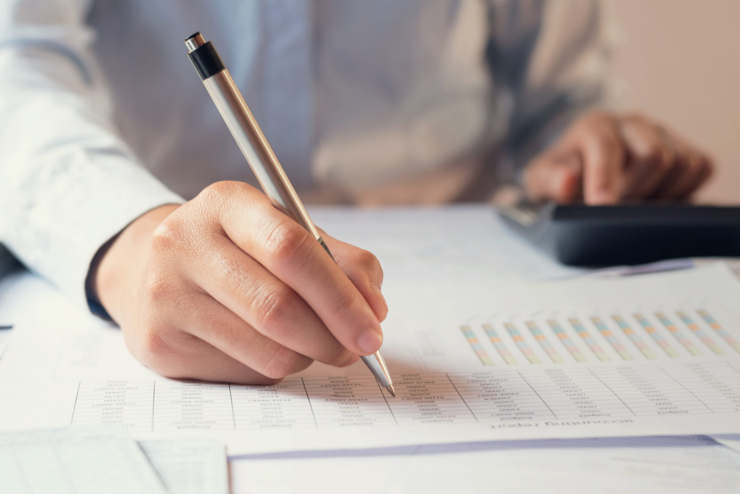 .accountant working on desk to using calculator with penaccountant working on desk to using calculator with pen